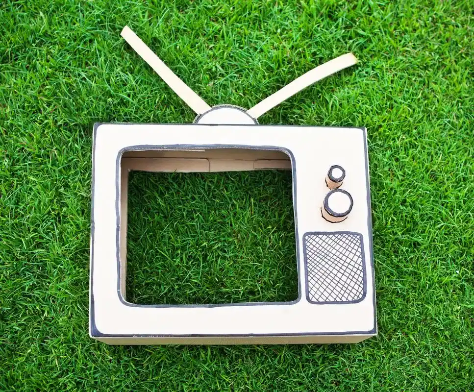 手工制作玩具电视,从纸框中在绿色草地上制作的手工制作玩具电视