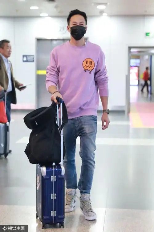 2017年10月27日,北京,何润东身着紫色卫衣,牛仔裤现身机场,口罩遮面