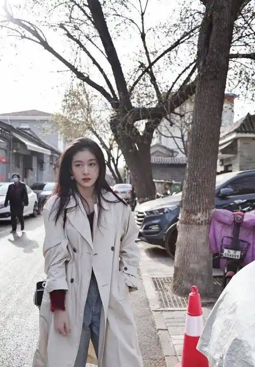 照片中,张雪迎身穿白色长衬衫,蓝色牛仔裤,白色鞋子,戴着深红色帽子.