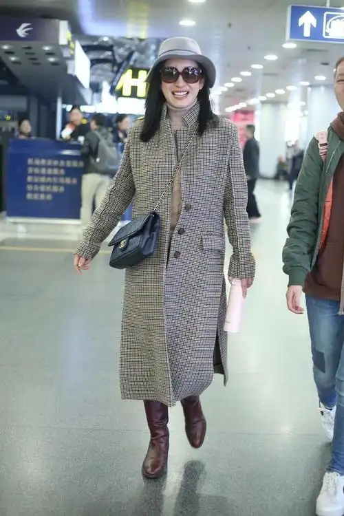 秦海璐手捧鲜花走机场衬衫叠穿高领衫黑色大衣又美又飒