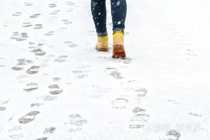在一个人的脚上,沿着冰冷的雪路面行走的后景.