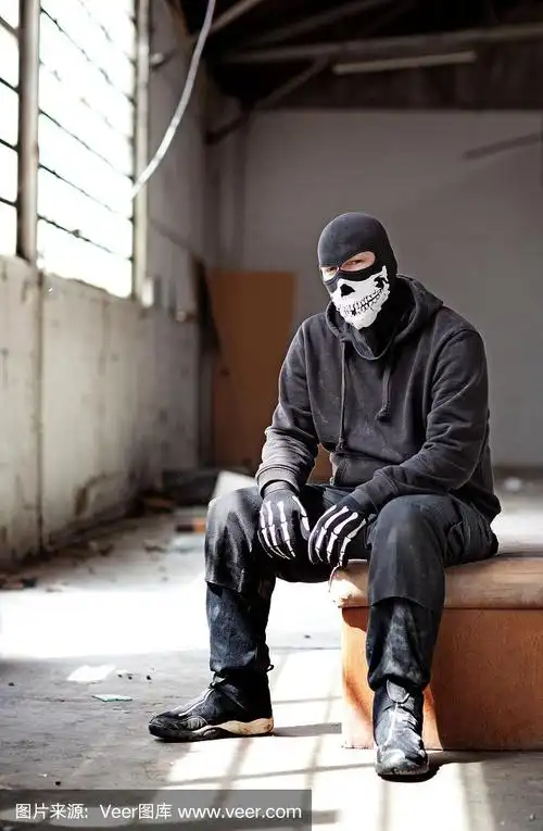 蒙面人坐在一个废弃的仓库里