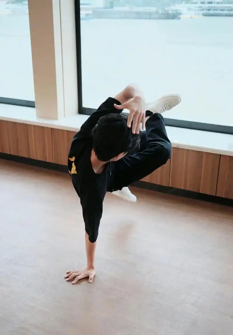 王一博身着热烈团服的地板动作定帧图,单手撑地,展现出强大的核心力量