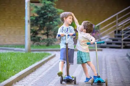 夏季滑板车两个可爱的男孩,参加骑滑板车,在公园里,室外夏季照片