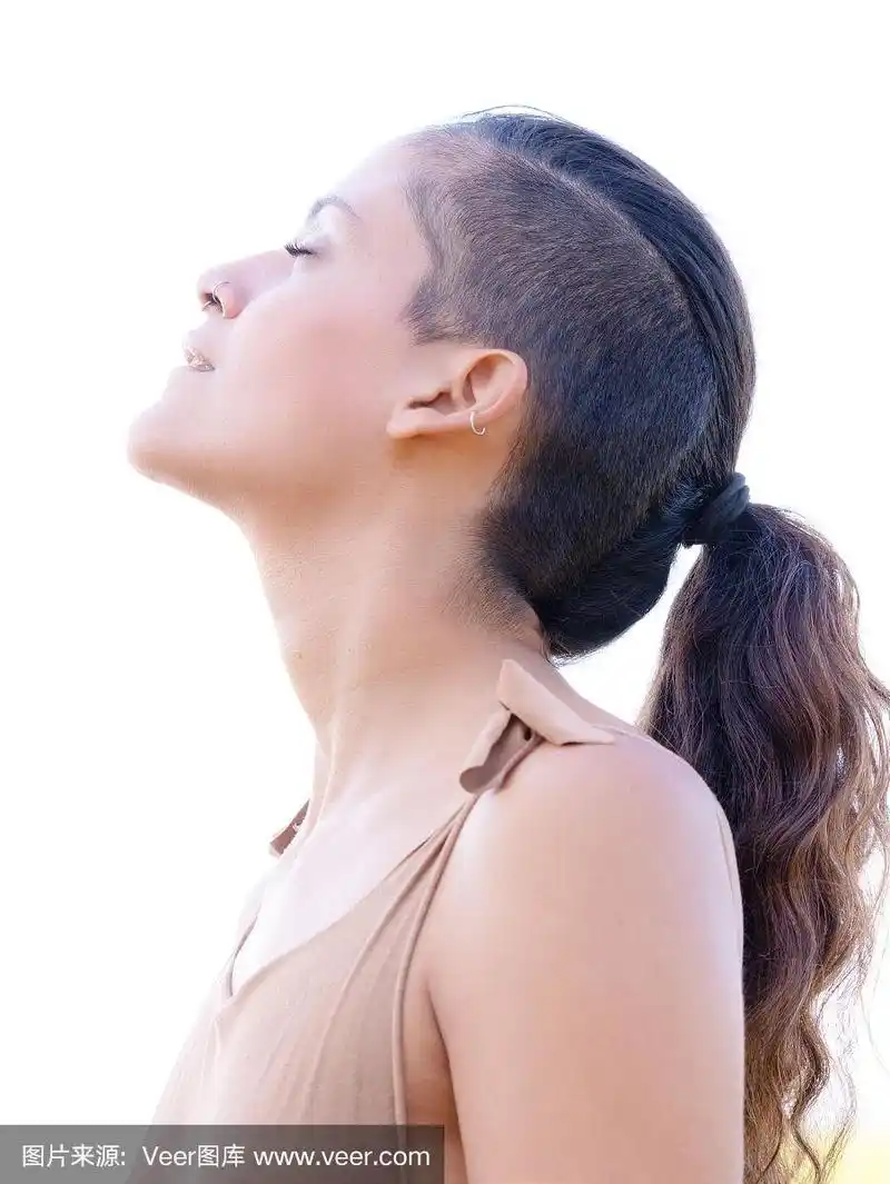 一个年轻的,波西米亚民族女孩的侧面肖像闭上眼睛和半剃了头和马尾辫
