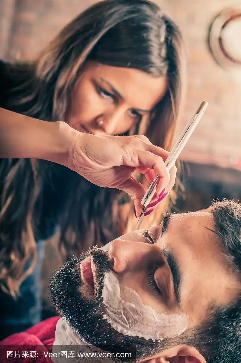 女理发师正在给客户刮胡子