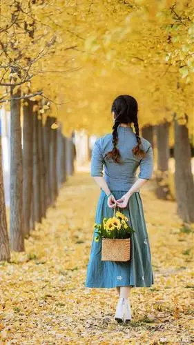 比如下图,身穿红裙子的模特款款走在秋林大道中,裙裙飞扬,长发飘飘