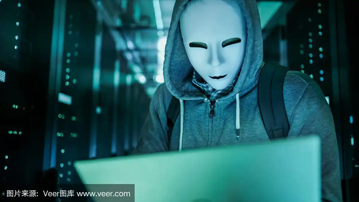 (中景)一个穿着帽衫的蒙面黑客站在满是机架服务器的数据中心中间,用