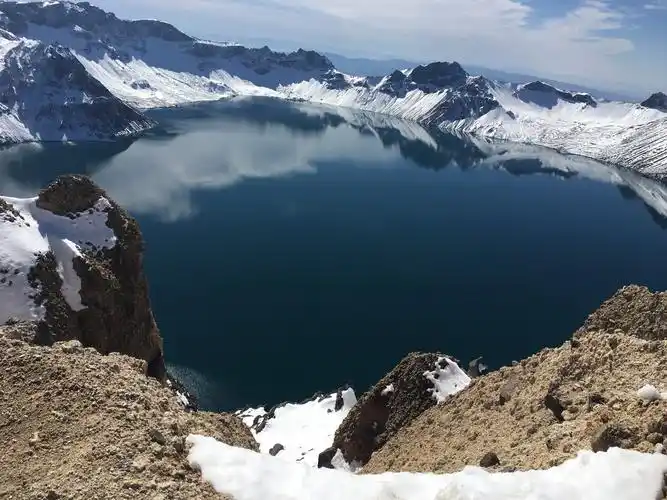 登上雪后的长白山主峰,俯瞰天池,池水湛蓝,宛如瑰丽温润的碧玉,晶晶