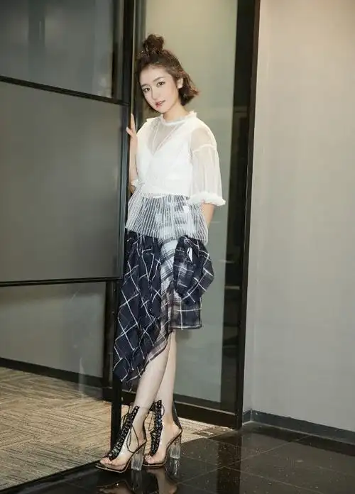 李兰迪身穿一件米色衬衫,搭配一条格子半身裙,脚穿一双黑色高跟