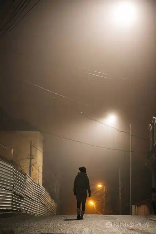 一个孤独的女人穿着外套走在雾蒙蒙的老城区里