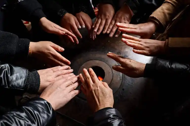 3月6日,坪子社区的"铁娘子军"在坪子社区村民胡丰安家内围炉烤火.