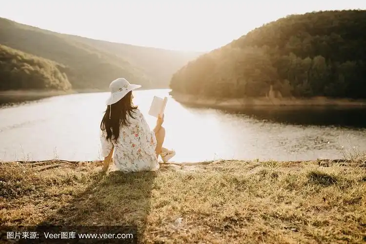 年轻优雅的感性女性坐在湖边看书