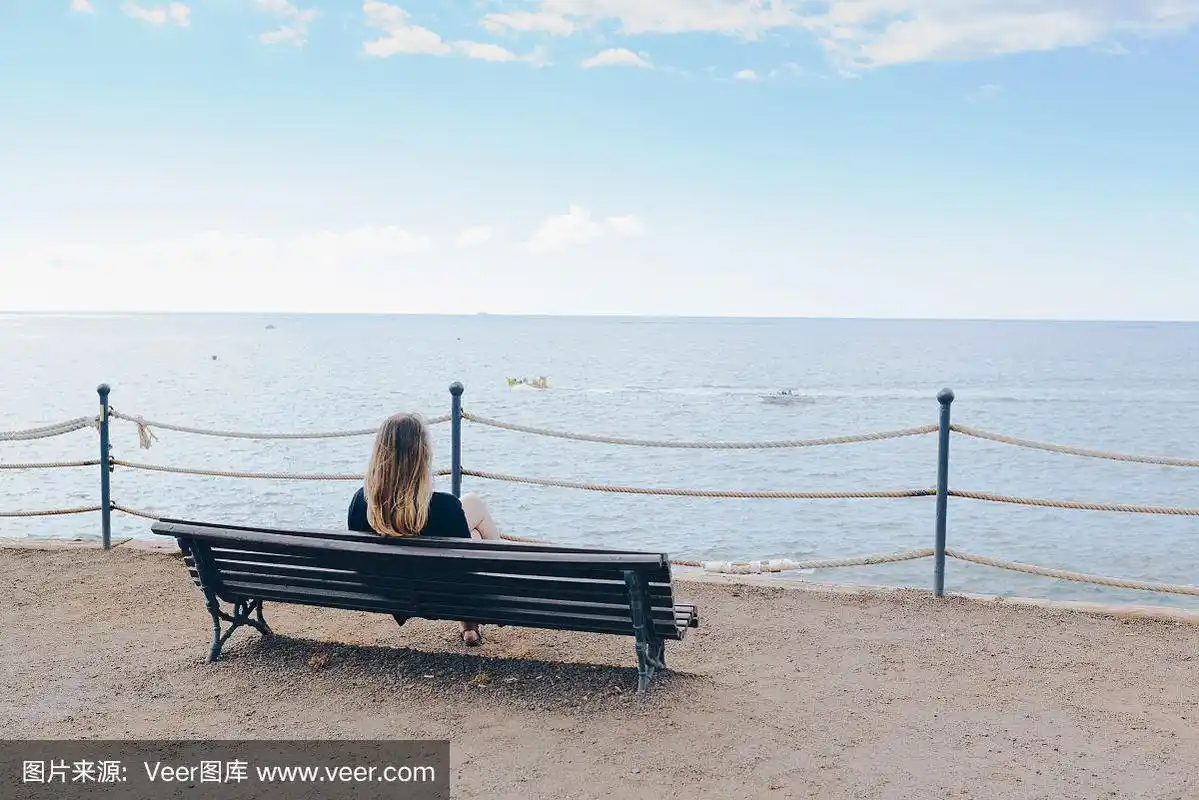 一个女人独自坐在海边的木凳上