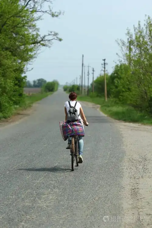 骑着一辆旧的生锈的自行车沿着乡间小路的年轻女子