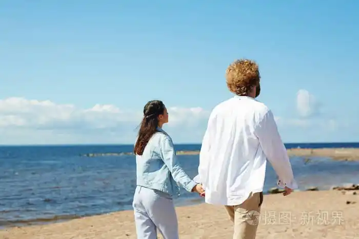 casualwear 快乐年轻夫妇在夏天散步时双手牵手的后视图照片-正版商用
