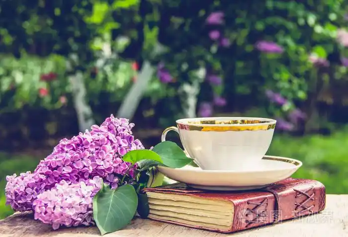 书, 杯茶和丁香花.香茶在花园里.浪漫的概念.复古随身携带