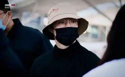 张艺兴行程饭拍图,身着深色毛衣配亮闪羽绒服,渔夫帽搭配边框眼镜