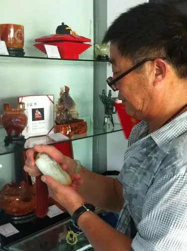 一老者在仔细观赏 "微雕第一人"常世琪大师的作品《数珠罗汉》