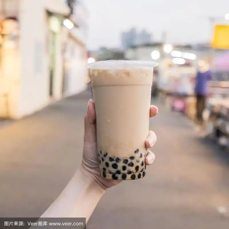 一名年轻女子正拿着塑料杯的红糖奶茶在台湾夜市,台湾美食,关门.