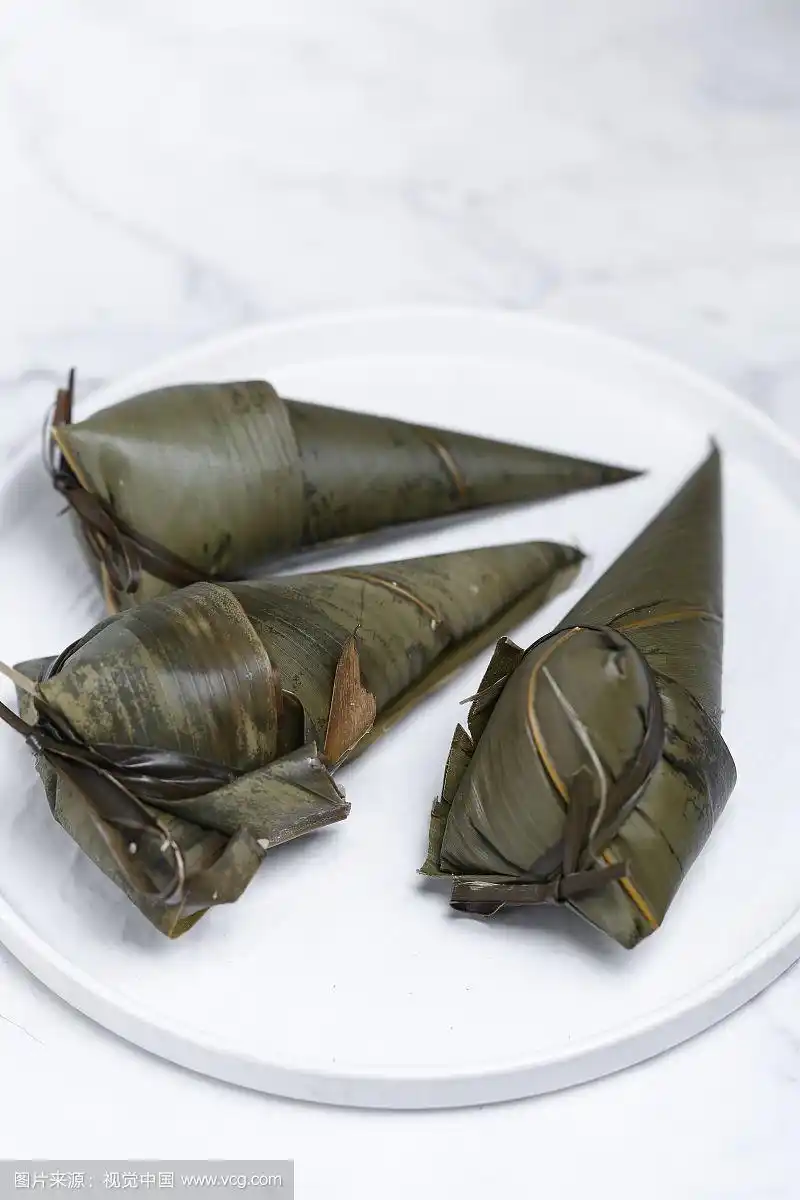 放在白色盘子上的手工三角粽