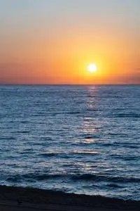 太阳从平静的蓝色海面升起.照片