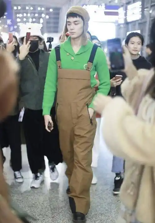 吴磊现身机场,穿绿色针织衫搭背带裤超可爱,身高182cm反差萌_衣服
