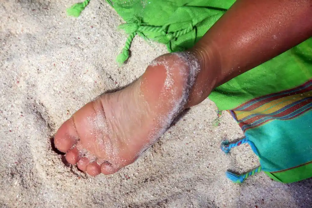 休息,女赤脚的腿弄脏在沙子中