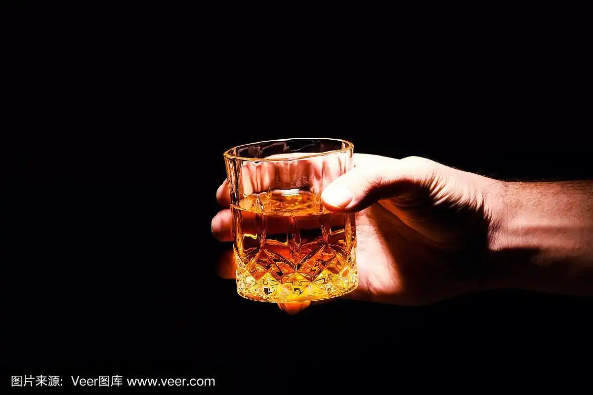 一个男人手里拿着威士忌酒杯