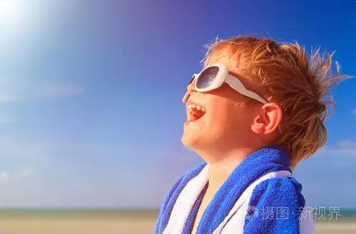 快乐的小男孩笑裹在沙滩巾上天空