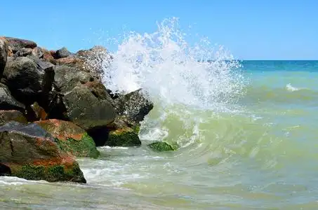 浪花拍打在沙滩上的大石头上照片