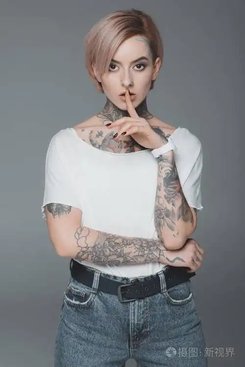 美丽的纹身女孩打手势沉默, 看着相机孤立在灰色