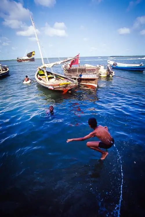 肯尼亚印度洋边的穆斯林小城拉穆,码头边在海里游泳的孩子们.