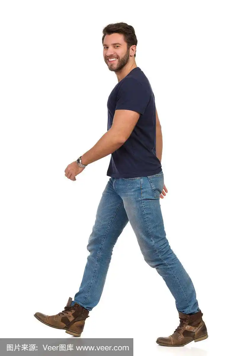 穿着蓝色t恤,牛仔裤和靴子的微笑行走的人.侧视图.