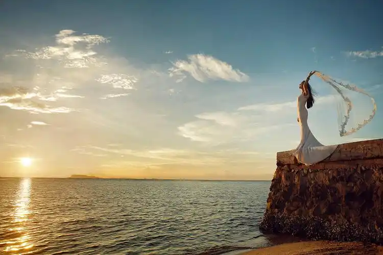 东方新娘站在海边岩石上图片