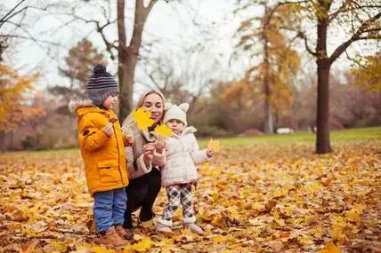 妈妈和两个小孩玩耍.温暖的冬天.明亮的秋天照片