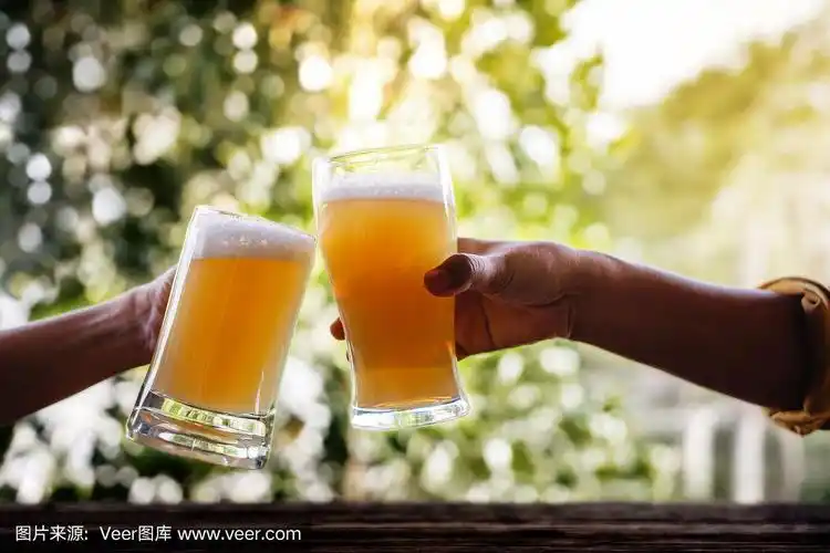 两个朋友在阳台上用杯子干杯和喝啤酒