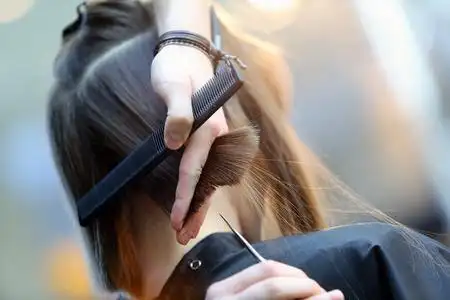 用剪刀修剪棕色头发的理发师照片