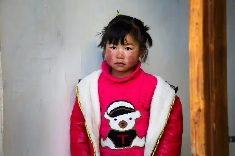 刚从屋里走出来的这孩子似乎刚从梦里醒来,带着高原红的脸蛋圆圆的