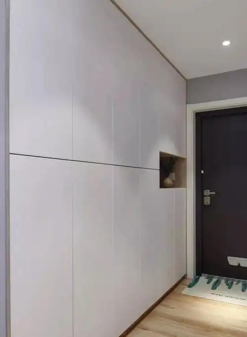 进门右侧是一整面墙的 嵌入式鞋柜 既拥有简约大方的外观 也满足了