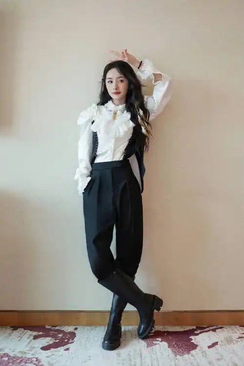 杨幂也穿着黑色的长筒靴,对着镜头摆出了剪刀手的造型,眼神依旧十分的