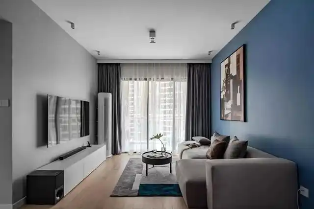 客厅在灰色电视墙 蓝色沙发墙,搭配木质地板,整体简约自然的家具