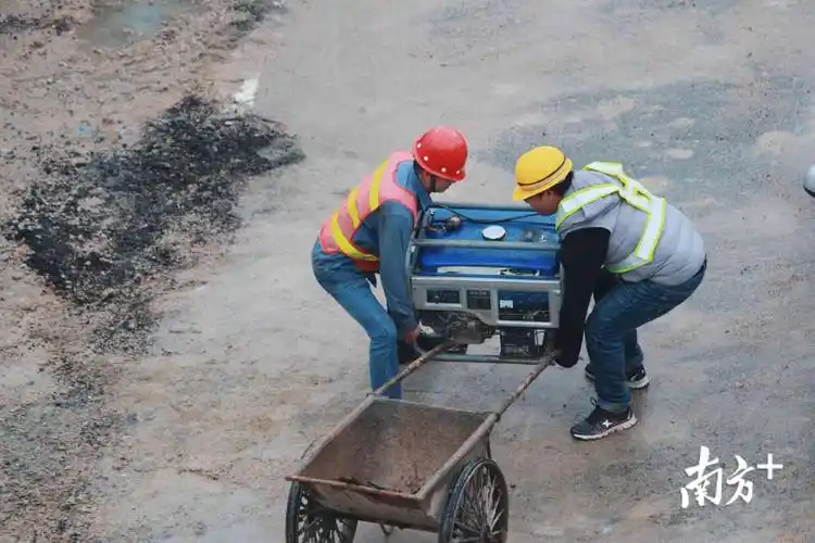 两名工地的工人将重物搬上推车.