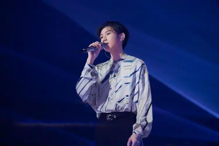 67中,王源身着设计感衬衫,幽蓝的灯光下,他手握黑色话筒,十指修长而