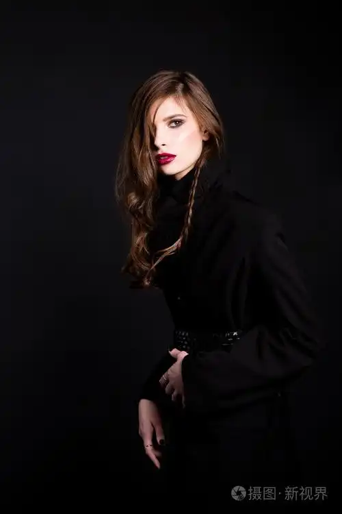 黑发的女人,穿着一件黑色的外套,与铺设和红红的嘴唇在黑色的背景