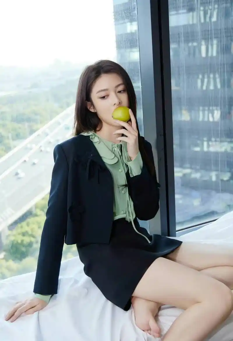 傅菁光着脚坐在阳台上,手里拿着一个俏皮可爱的小水果.[坏笑]