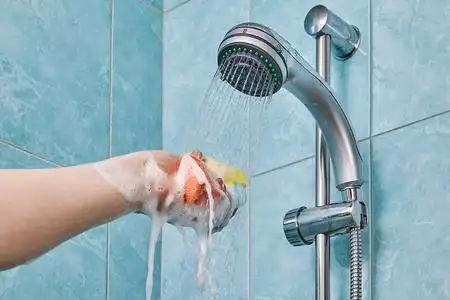 淋浴喷头下的手挤压多色海绵照片