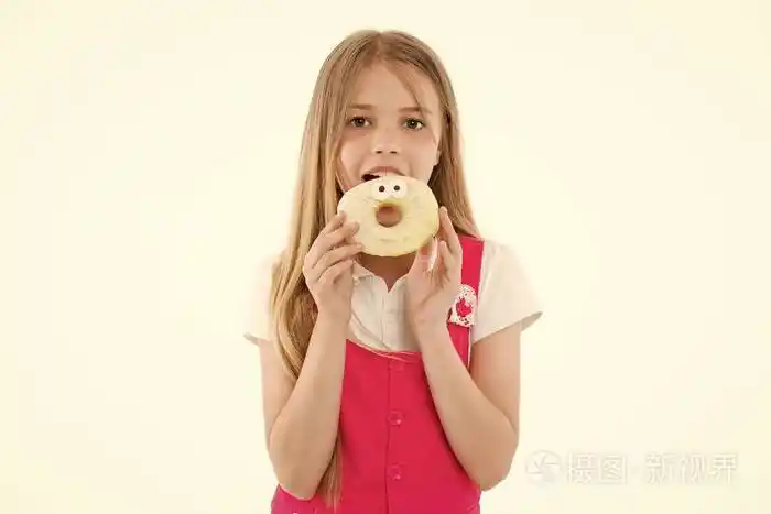 小女孩吃着白面包圈戴着透明环形甜甜圈的孩子吃垃圾食品的孩子点心和