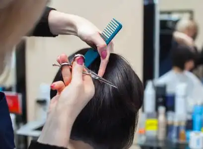 火锅店片头理发师对理发与热剪刀片头发一个年轻的女孩,一个在一家