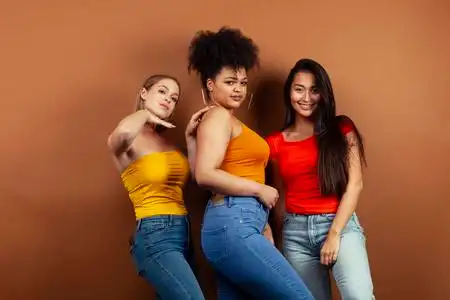 年轻漂亮的多民族女孩在棕色背景下摆出欢快的姿势,生活方式符合人们